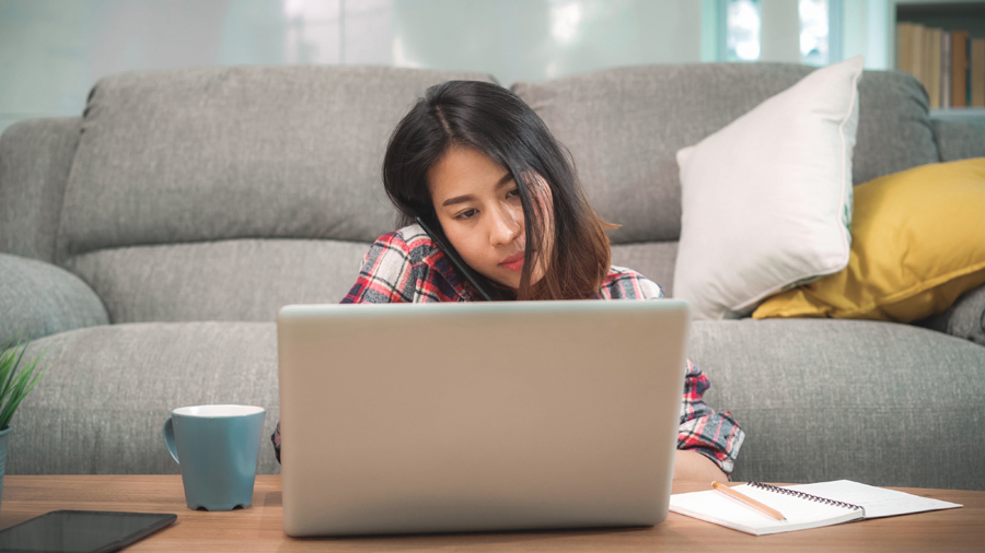 woman searching on her laptop while making a call