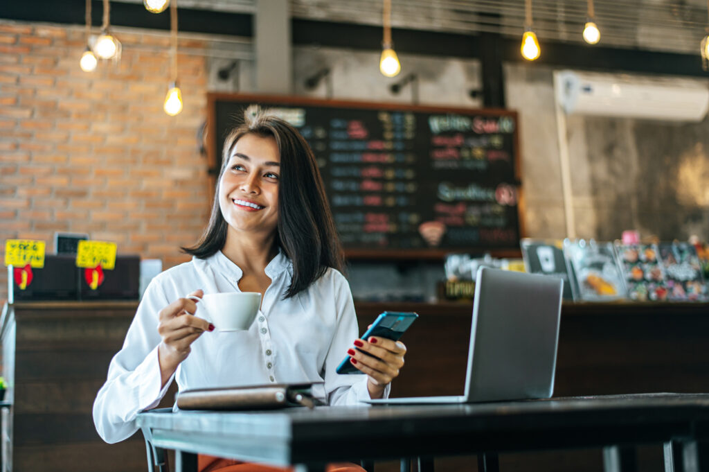 woman sitting happily working with a smartphone in a coffee shop