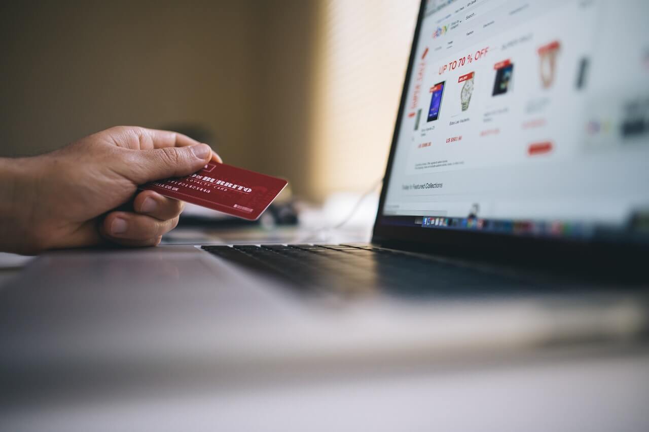 Black and Gray Laptop Computer With Turned-on Screen Beside Person Holding Red Smart Card in Selective