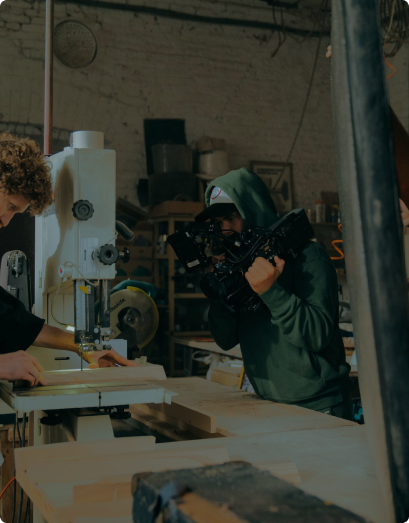 videographer taking a video of a man sewing