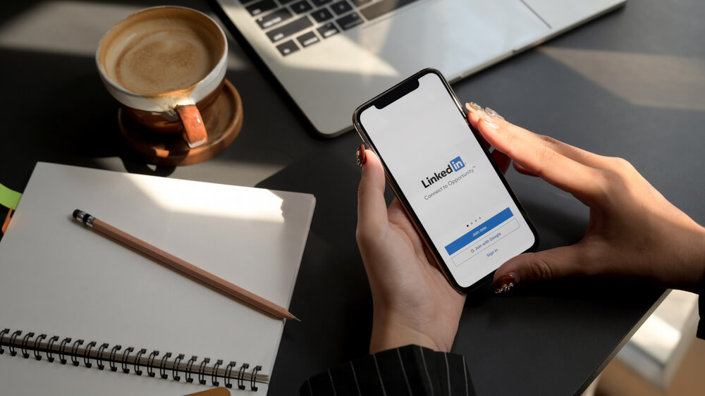 female using iPhone with LinkedIn screen