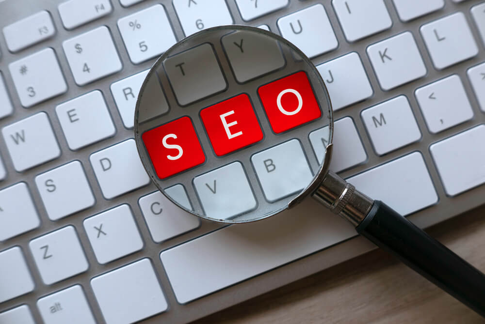 Red letters spelling seo under a magnifying glass