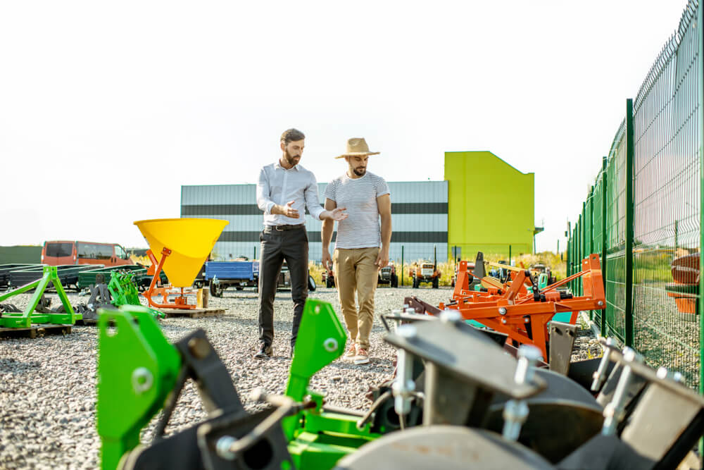 two young men talking while looking at agricultural machinery