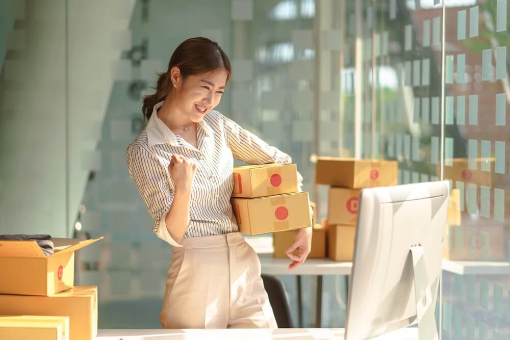 happy female small business owner holding product packages