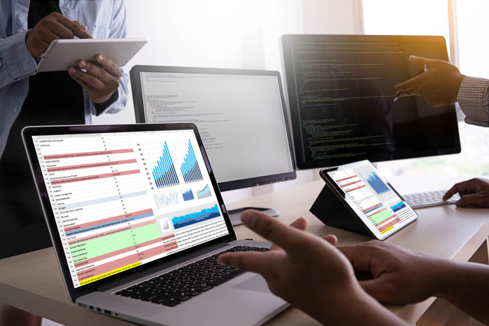 Close up of hand pointing to laptop showing data with graphs