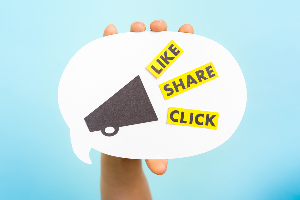 hand holding speech bubble with megaphone and words like, share, click