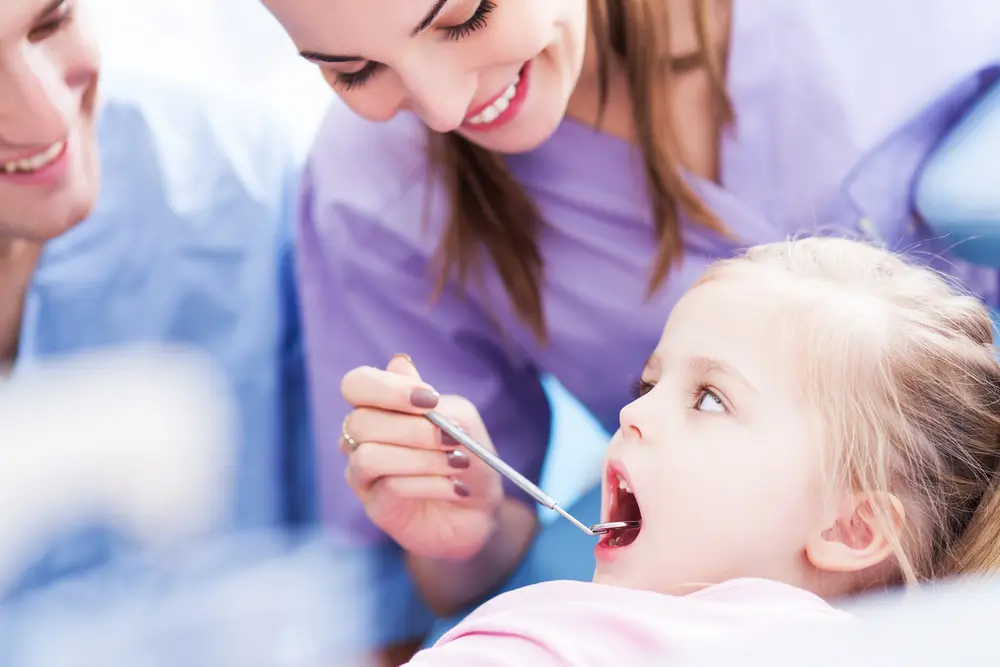 A little girl having her teeth checked by dental professionals